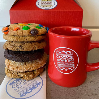 Stack of cookies and a red mug with 'Cookie Monstah' branding on a wooden surface.