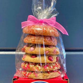 Stack of colorful cookies tied with a pink ribbon, visible through a clear plastic packaging.
